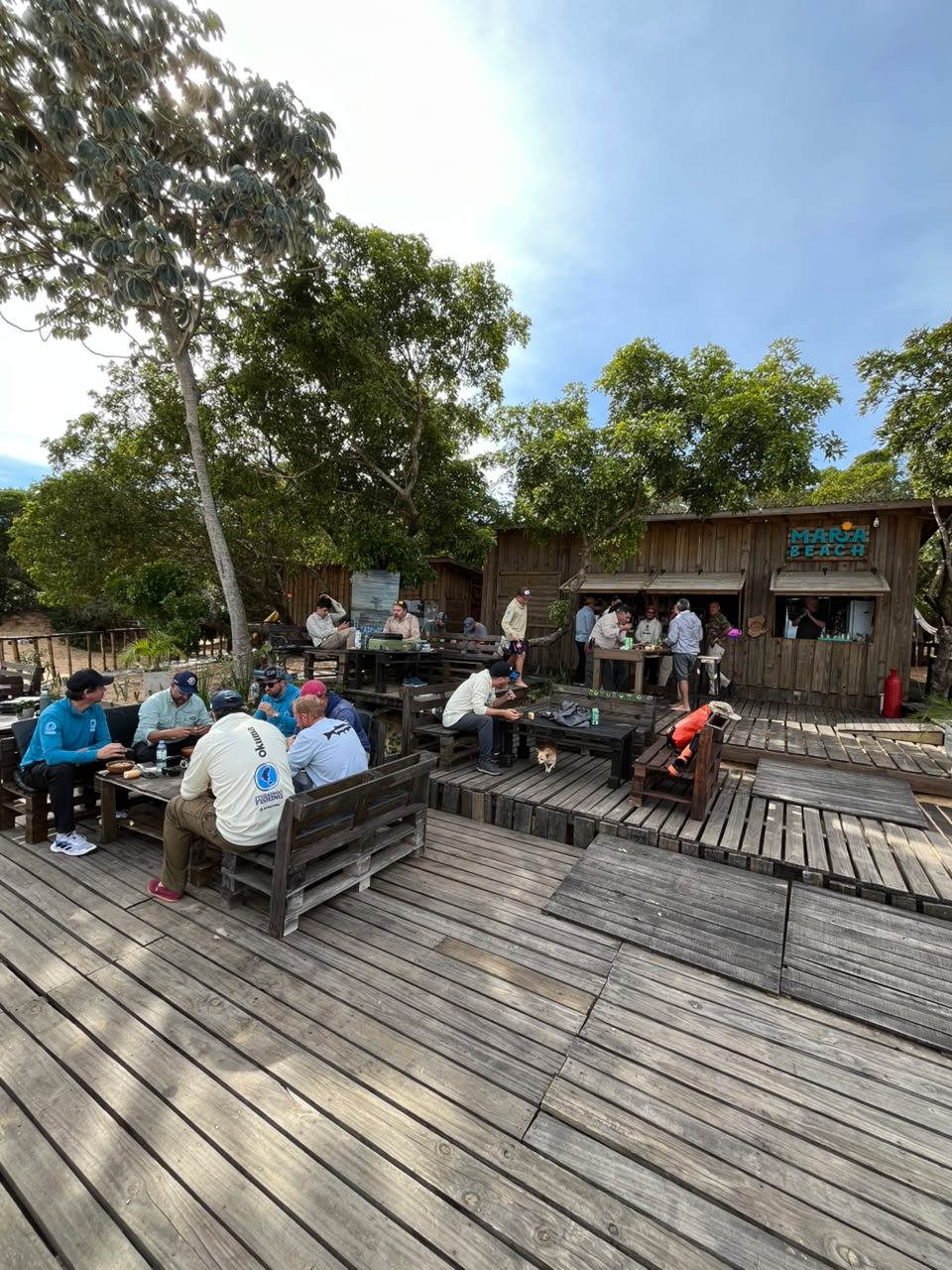 Terraza de madera, mesas y visitantes en María Beach